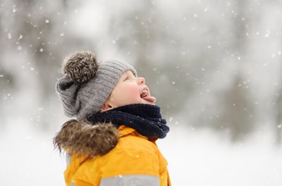 Little boy catching snowflakes on his tongue.
