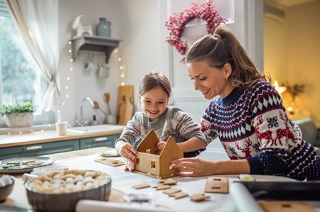 Mother & daughter building gingerbread house