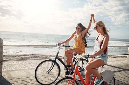 Friends riding bike next to the beach